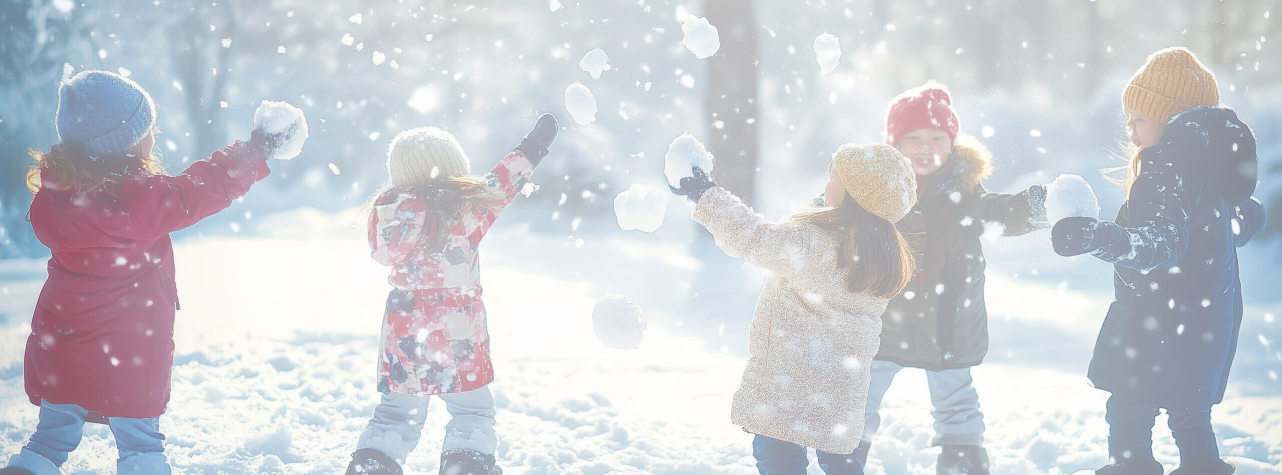 Children joyfully playing in a snowy landscape, creating snowballs during a bright winter day surrounded by shimmering snowflakes